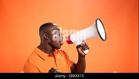 Black man, megaphone and voice in studio for announcement, broadcast or opportunity. Join us, mockup space or African speaker screaming with noise Stock Photo