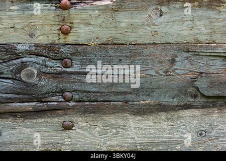 The close-up view reveals the intricate surface of aged wooden planks with rusted nails, highlighting natural wear and rustic charm. Stock Photo