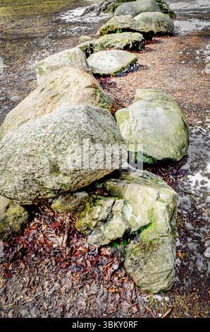 Close-up of a row of stones next to light snow in a field Stock Photo