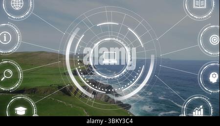 Displaying circular digital interface over coastal cliffs, churning sea with laptop and tech icons Stock Photo
