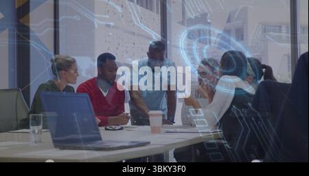 Six colleagues collaborating around long white table in modern office, with laptops and coffee cups Stock Photo