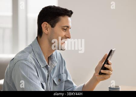 Happy smiling casual gen z man using modern mobile telephone Stock Photo