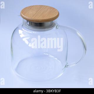 Stylish transparent tea pot with wooden lid on white background Stock Photo