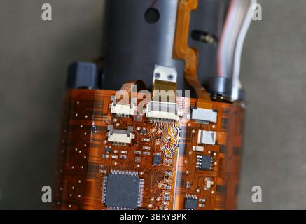 Macro shot of DSLR lens circuit board with flex cables and microchips, revealing detailed internal camera electronics. Stock Photo