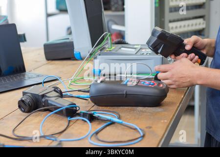 VINKOVCI, CROATIA, 06.20.2018:Technician working with testing equipment on a wooden desk, surrounded by various electronic tools. The setting showcase Stock Photo