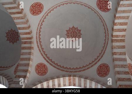 A low-angle shot of a dome ceiling with red geometric patterns and striped pillars, showcasing the architectural design and decorative elements of the structure. Stock Photo