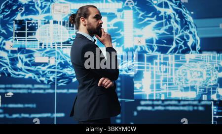 Young businessman reviews artificial intelligence neural networks on dashboard, using high tech automation tools for coding, analytics and deep learning for strategic development. Camera A. Stock Photo