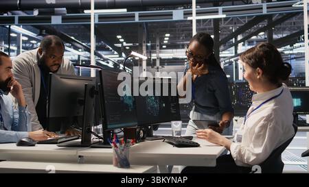 Smiling technicians doing fist bump in data center after successful deployment of AI tools. Server room engineering team celebrate completion of machine learning system integration, camera A Stock Photo