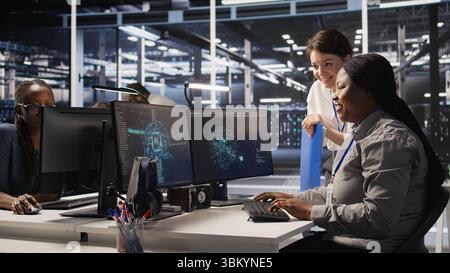 Data center team leader and IT expert reviewing performance dashboards of AI equipment rigs. Server room manager oversee system administrator examining machine learning algorithms on screen, camera A Stock Photo