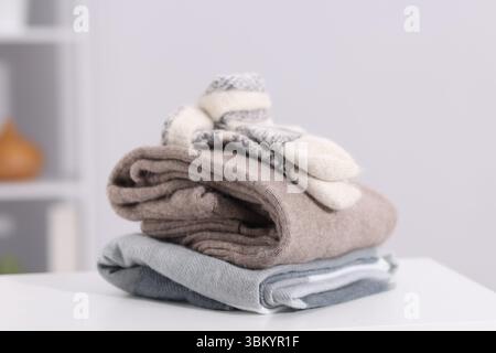 Stack of wool clothes on white table indoors Stock Photo