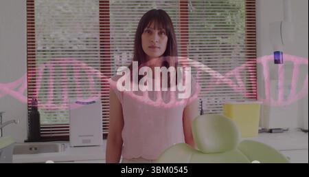 Standing woman in pink blouse in dental office, with dental chair headrest and DNA helix overlay Stock Photo