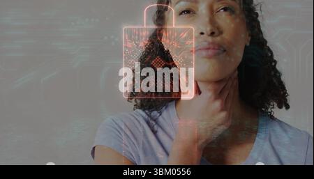 Touching throat woman wearing grey T-shirt showing padlock icon in studio, with circuit overlays Stock Photo