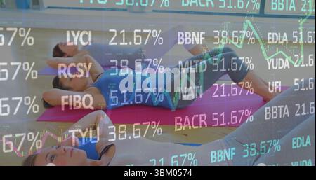 Three women in sportswear doing abdominal crunches on mats in studio, with ticker overlays Stock Photo