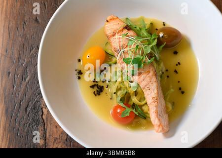 Grilled salmon fillet served over zucchini noodles in butter sauce on white plate Stock Photo