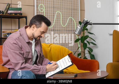 Young happy male composer writing notes in music studio Stock Photo