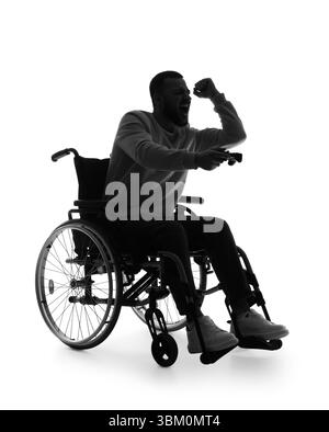 Silhouette of young man in wheelchair playing video game on white background Stock Photo