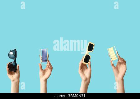Female hands holding mini deck chairs with sunglasses on blue background Stock Photo