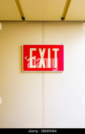 Red exit sign on wall, USA Stock Photo