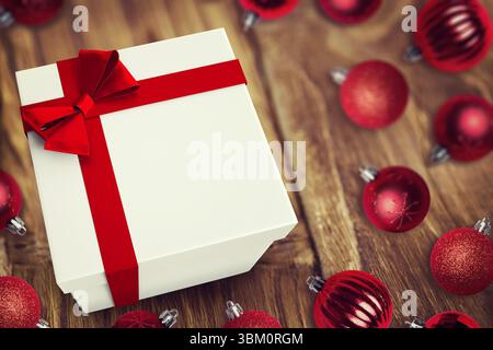 3D render showing white gift box is sitting on wooden tabletop with red ribbon, red baubles Stock Photo