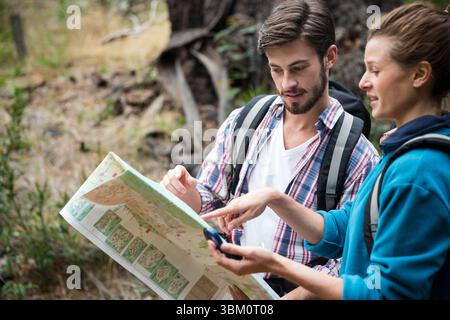 Couple discussing over map in forest Stock Photo