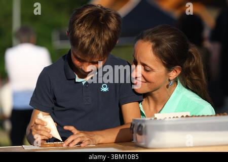 Mother and son decorating gingerbread cookies together outdoors Stock Photo