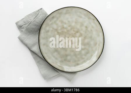 An empty grey textured plate with a napkin on a white table Stock Photo