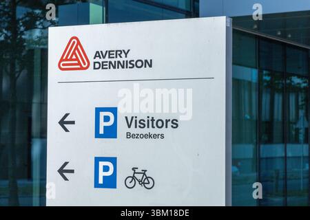 A clear Avery Dennison sign directs visitors and cyclists to parking, positioned in front of a modern corporate building with glass windows. Leiden, N Stock Photo