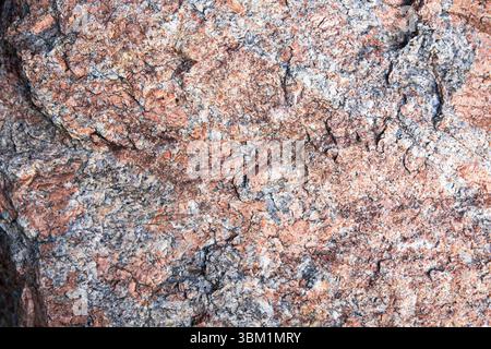 Detailed close-up of a granite stone surface with pink, gray, and white mineral patterns. Ideal natural background for design, construction, geology, Stock Photo