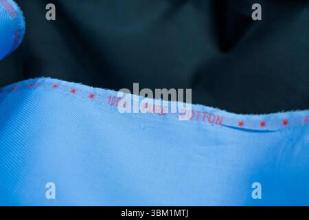 Close-up view of a piece of light blue cotton fabric. The fabric's texture is subtly visible, showing a fine weave.  A red label clearly displays '100 Stock Photo