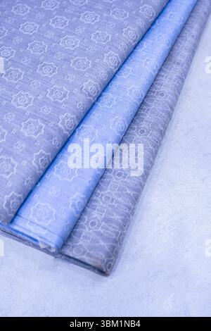 The image shows three folded pieces of patterned fabric in shades of blue and gray.  The textiles feature a subtle, embossed floral design. Stock Photo