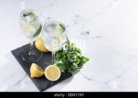 Hugo Cocktail with Lemon, Mint, and Ice in a Wine Glass on marble background Stock Photo