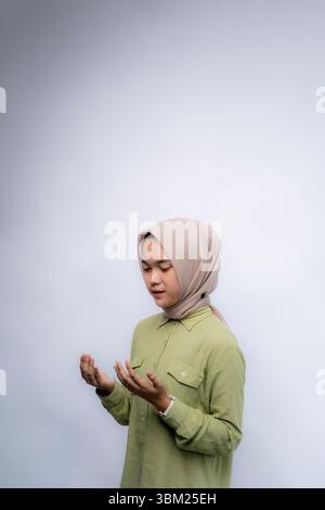 Prayer. Portrait Of Young asian woman wearing hijab raised both hands in prayer at Copy Space Advertising Your Text, Standing Isolated Over white Stud Stock Photo