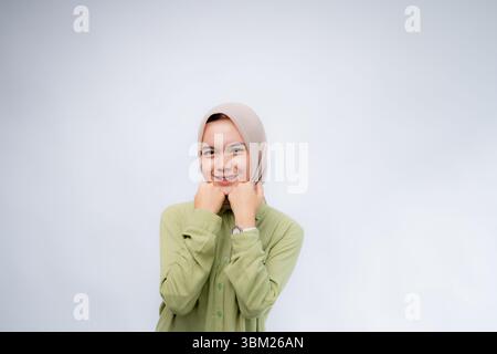 Excited. Portrait of young asian woman wearing hijab clenched his fist on his forehead at Copy Space Advertising Your Text, Standing Isolated Over whi Stock Photo