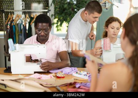 Young male teacher helping students sew Stock Photo