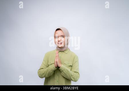 Smiling young Asian Muslim woman gesturing Eid Mubarak greeting isolated over white background Stock Photo