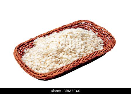 Overflowing Vialone Nano rice grains in a small wicker basket create a visually appealing display against a clean white background, highlighting the q Stock Photo