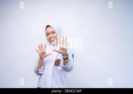 Surprised Female Indonesian high school student in white and grey uniform shouting while looking at the camera over white background Stock Photo
