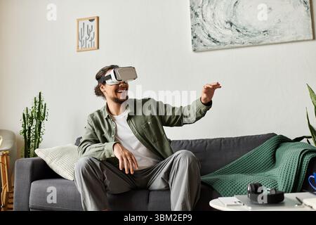 Young man at home engages with virtual reality, expressing joy and immersive enjoyment. Stock Photo