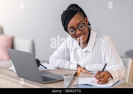 Cheerful business lady attending webinar, using laptop at home Stock Photo