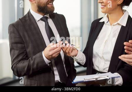 Cropped image of businessman giving pen to businesswoman for signing documents Stock Photo