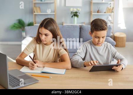 Brother and sister studying together at home, busy doing homework Stock Photo