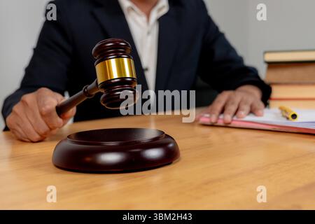 Selective focus on judge’s hand with gavel, symbolizing legal authority in business decision-making. Stock Photo