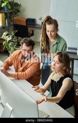 Young Adult Multiethnic Team Analyzing Neural Network Data on Desktop Computer Stock Photo