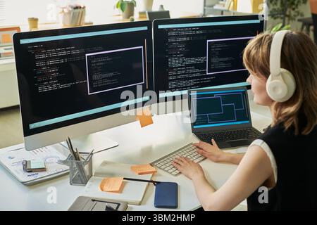 Woman Developing Neural Network Code on Multiple Computer Screens Stock Photo