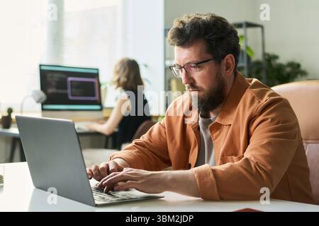 Man Developing Neural Network on Laptop in Office Stock Photo