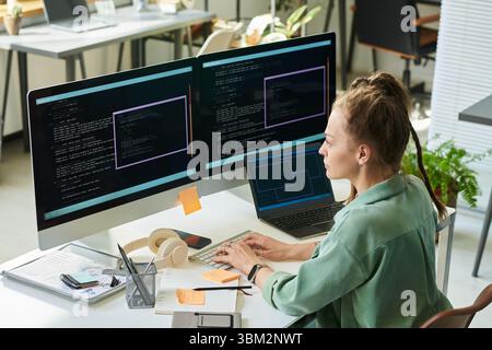 Young Caucasian Woman Developing Neural Network Code on Multiple Monitors Stock Photo