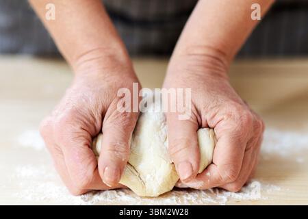 Female hands kneading dough, woman cooking in kitchen Stock Photo