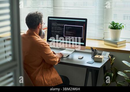 Caucasian Young Adult Man Developing Neural Network Code on Desktop Computer Stock Photo