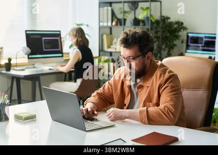 Caucasian Young Adult Man Developing Neural Network on Laptop in Office Stock Photo