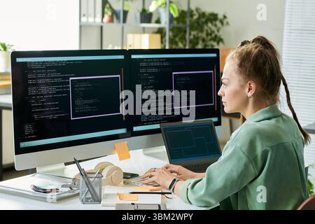 Young Caucasian Woman Developing Neural Network Code on Dual Monitors Stock Photo